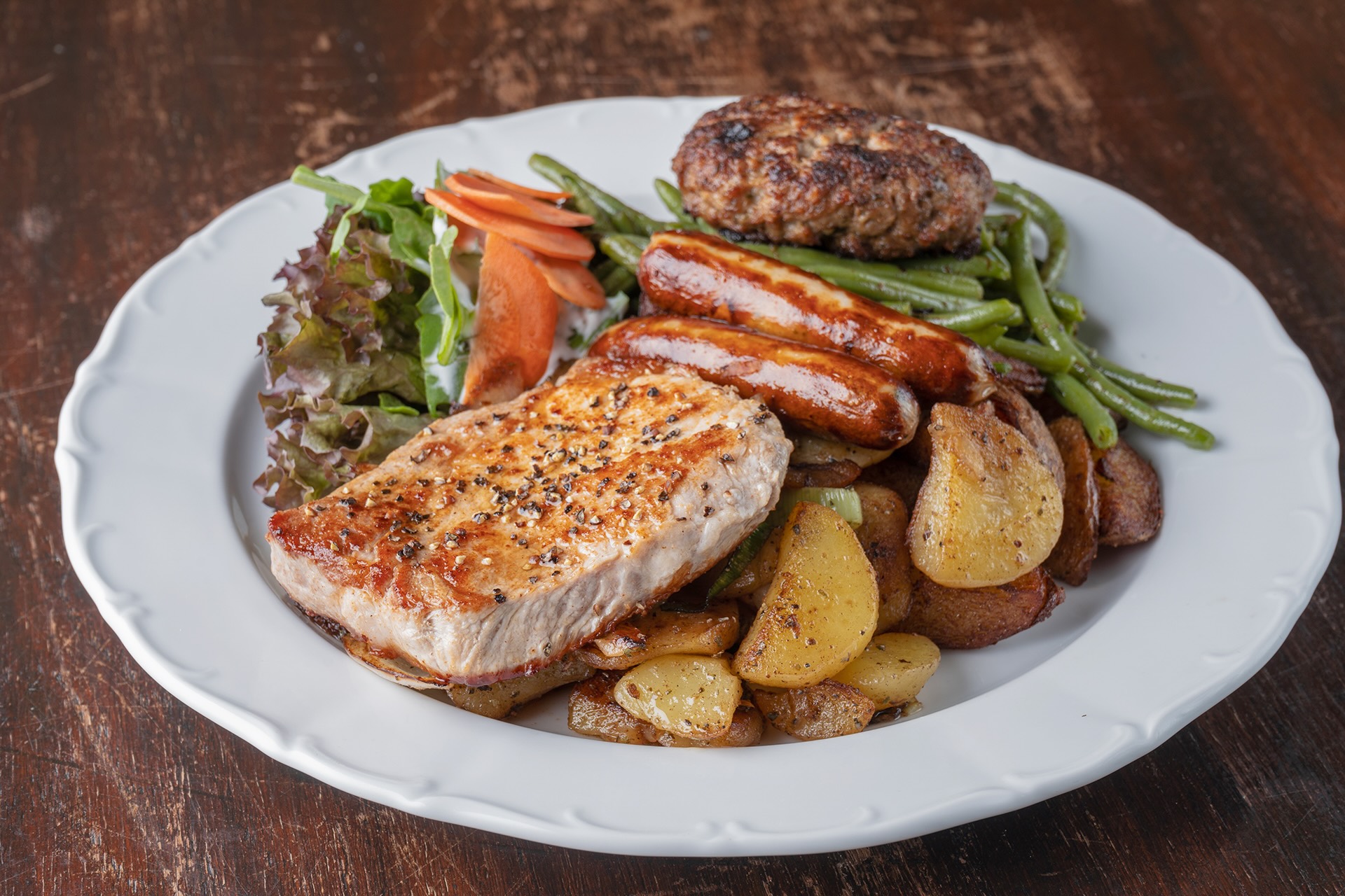 Schweinesteak mit Bratwürsten, Boulette, knusprigen Bratkartoffeln und grünen Bohnen